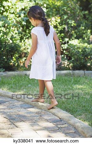 Stock Image - Rear view of a little girl walking in the garden. Fotosearch
