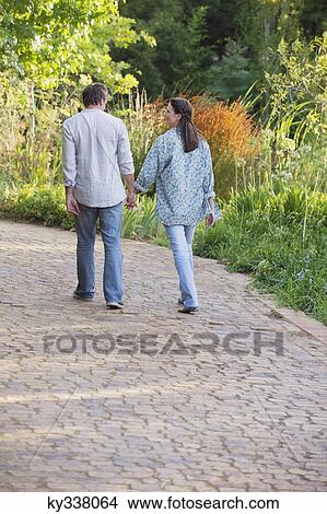 Picture - Rear view of a mature couple walking in a garden. Fotosearch