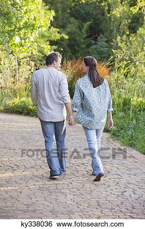 Stock Photograph - Rear view of a mature couple walking in a garden. Fotosearch