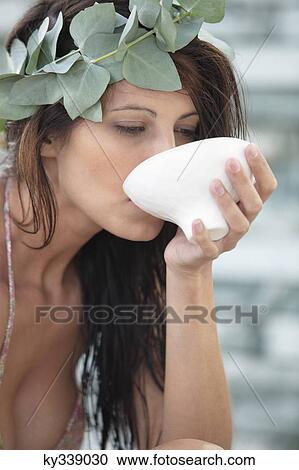 Stock Image - Close-up of a woman drinking from a bowl. Fotosearch
