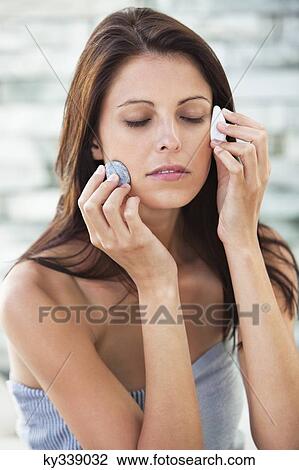 Stock Image - Close-up of a woman touching stones on her face. Fotosearch