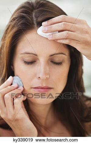 Stock Photo - Close-up of a woman touching stones on her face. Fotosearch