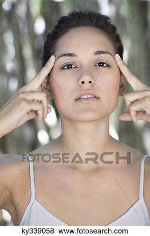 Portrait of a beautiful young woman with fingers on temples View Large Photo Image Stock Photo - Portrait of a beautiful young woman with fingers on temples. Fotosearch