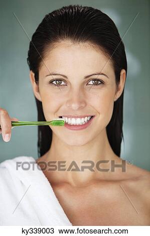 Stock Image - Portrait of a woman brushing her teeth. Fotosearch