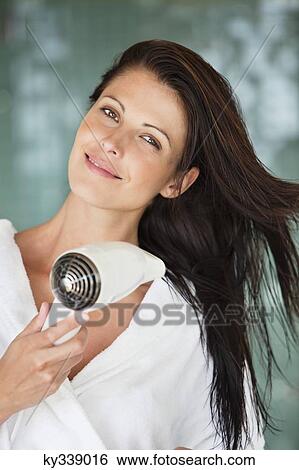 Portrait of a woman drying her hair with a hair dryer View Large Photo Image Stock Photograph - Portrait of a woman drying her hair with a hair dryer. Fotosearch