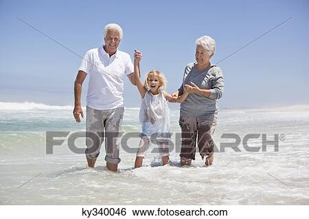 Girl enjoying on the beach with her grandparents View Large Photo Image Stock Photograph - Girl enjoying on the beach with her grandparents. Fotosearch