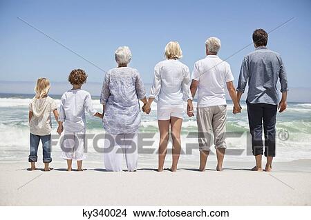 Rear view of a family looking at sea view from beach View Large Photo Image Picture - Rear view of a family looking at sea view from beach. Fotosearch