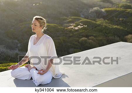Mid adult woman meditating View Large Photo Image Picture - Mid adult woman meditating. Fotosearch