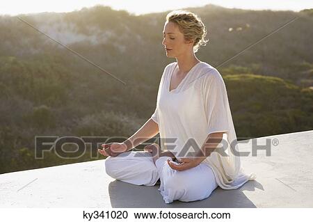 Mid adult woman meditating View Large Photo Image Stock Image - Mid adult woman meditating. Fotosearch