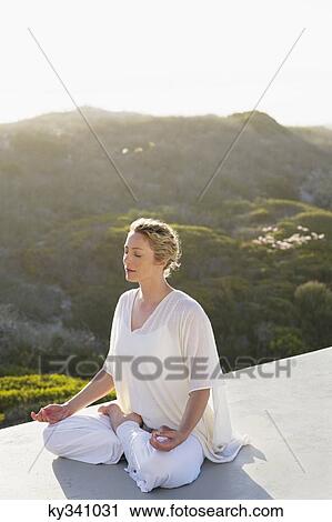 Mid adult woman meditating View Large Photo Image Stock Image - Mid adult woman meditating. Fotosearch