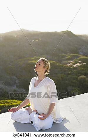 Mid adult woman meditating View Large Photo Image Stock Image - Mid adult woman meditating. Fotosearch