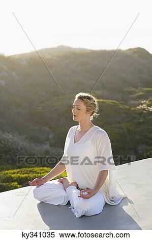 Mid adult woman meditating View Large Photo Image Stock Photography - Mid adult woman meditating. Fotosearch