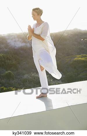 Stock Photo - Mid adult woman practicing yoga. Fotosearch