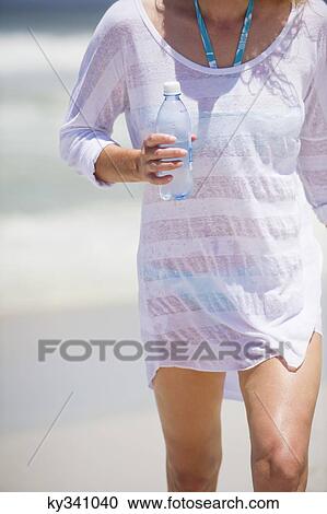 Mid section view of a woman carrying a water bottle View Large Photo Image Stock Image - Mid section view of a woman carrying a water bottle. Fotosearch