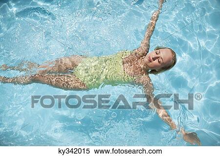 Beautiful woman floating in a swimming pool View Large Photo Image Stock Photography - Beautiful woman floating in a swimming pool. Fotosearch