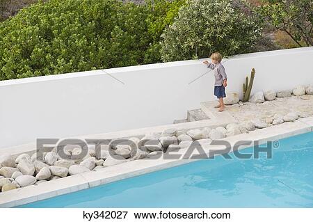 Stock Photo - Boy standing at the poolside pool. Fotosearch