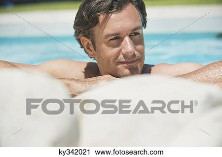 Stock Image - Man resting his head at the poolside. Fotosearch