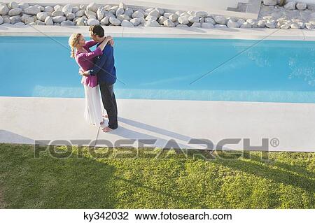 Mid adult couple embracing each other at the poolside View Large Photo Image Stock Image - Mid adult couple embracing each other at the poolside. Fotosearch