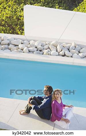 Mid adult couple sitting back to back at the poolside View Large Photo Image Stock Image - Mid adult couple sitting back to back at the poolside. Fotosearch
