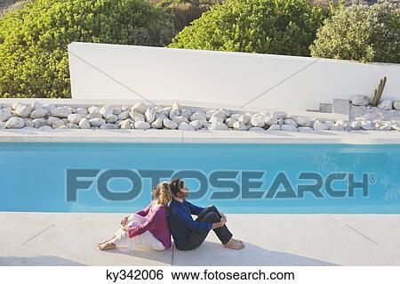 Mid adult couple sitting back to back at the poolside View Large Photo Image Stock Photograph - Mid adult couple sitting back to back at the poolside. Fotosearch