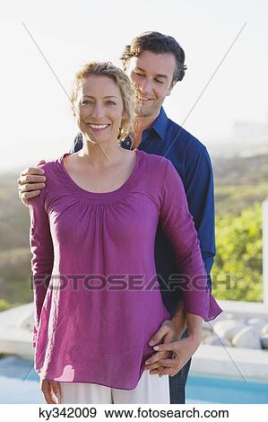 Mid adult couple standing at the poolside and smiling View Large Photo Image Stock Photo - Mid adult couple standing at the poolside and smiling. Fotosearch