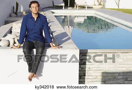 Mid adult man sitting on the terrace near a swimming pool View Large Photo Image Stock Photo - Mid adult man sitting on the terrace near a swimming pool. Fotosearch