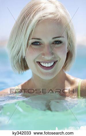 Stock Image - View of beautiful woman smiling in pool. Fotosearch