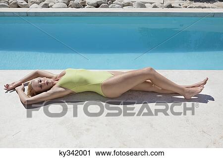 Woman sunbathing at poolside View Large Photo Image Stock Image - Woman sunbathing at poolside. Fotosearch