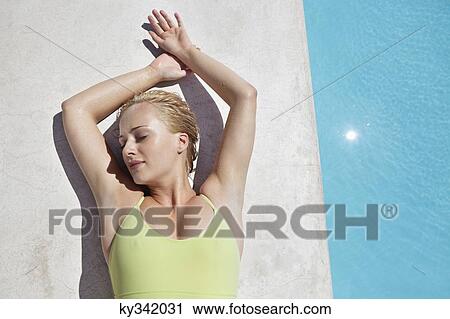 Woman sunbathing at poolside View Large Photo Image Stock Image - Woman sunbathing at poolside. Fotosearch