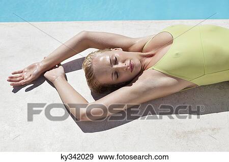 Woman sunbathing at poolside View Large Photo Image Stock Photo - Woman sunbathing at poolside. Fotosearch