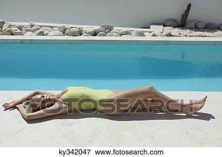 Stock Photo - Woman sunbathing at poolside. Fotosearch