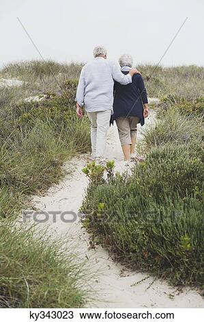 Rear view of a senior couple walking on the beach View Large Photo Image Stock Image - Rear view of a senior couple walking on the beach. Fotosearch