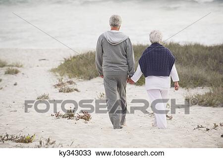 Rear view of a senior couple walking on the beach View Large Photo Image Stock Image - Rear view of a senior couple walking on the beach. Fotosearch