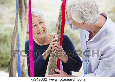 Senior couple standing near a decorated tree and smiling View Large Photo Image Stock Image - Senior couple standing near a decorated tree and smiling. Fotosearch