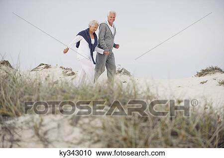 Senior couple walking on the beach View Large Photo Image Stock Image - Senior couple walking on the beach. Fotosearch