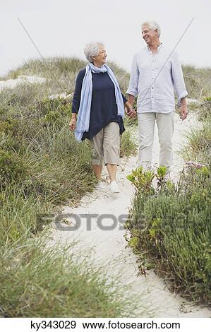 Senior couple walking on the beach with holding hands of each other View Large Photo Image Stock Photo - Senior couple walking on the beach with holding hands of each other. Fotosearch