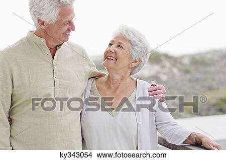 Picture - Senior man standing with his arm around a senior woman. Fotosearch