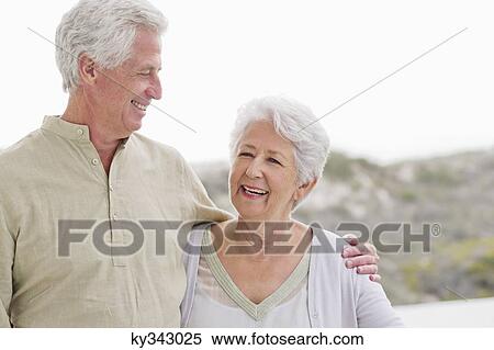 Stock Photography - Senior man standing with his arm around a senior woman. Fotosearch