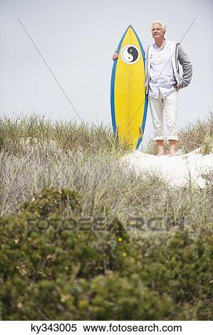 Senior man standing with surfboard on the beach View Large Photo Image Stock Photography - Senior man standing with surfboard on the beach. Fotosearch
