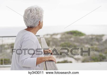 Senior woman standing at a balcony View Large Photo Image Stock Image - Senior woman standing at a balcony. Fotosearch