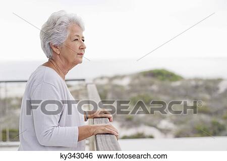 Senior woman standing at a balcony View Large Photo Image Stock Photograph - Senior woman standing at a balcony. Fotosearch