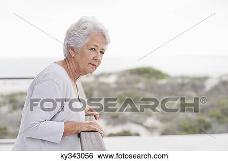 Senior woman standing at a balcony View Large Photo Image Stock Photograph - Senior woman standing at a balcony. Fotosearch