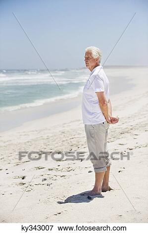 Stock Photo - Side profile of a senior man standing on the beach. Fotosearch
