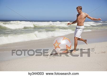 Man kicking ball on the beach View Large Photo Image Stock Image - Man kicking ball on the beach . Fotosearch