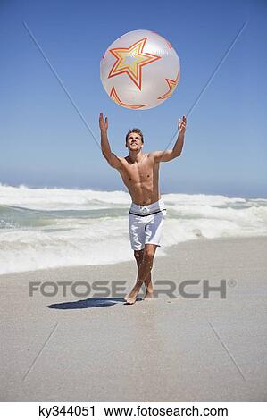 Stock Image - Man playing with beach ball. Fotosearch
