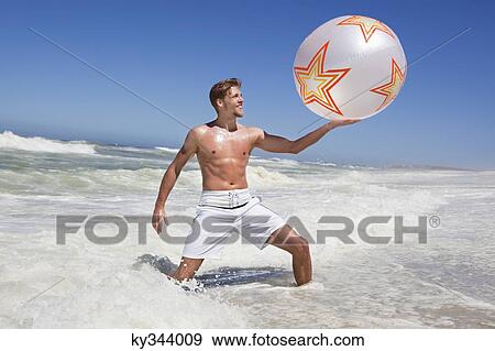 Stock Photo - Man playing with beach ball. Fotosearch