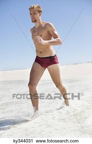 Stock Image - Man running on the beach. Fotosearch