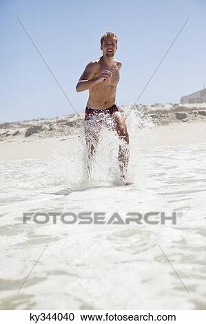 Stock Image - Man running on the beach. Fotosearch