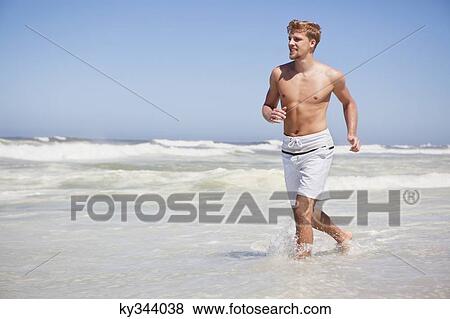 Man running shirtless on the beach View Large Photo Image Stock Photo - Man running shirtless on the beach. Fotosearch