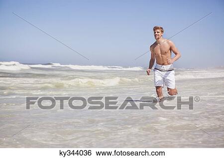Man running shirtless on the beach View Large Photo Image Stock Photograph - Man running shirtless on the beach. Fotosearch